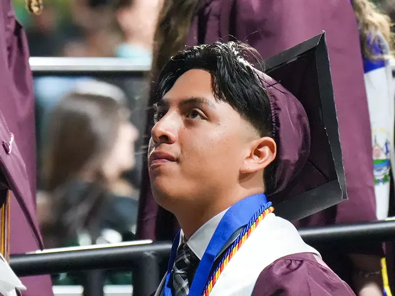 Student in graduation robe looking at stage