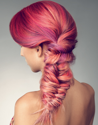Side profile of a person with vibrant pink hair styled in a braided updo.